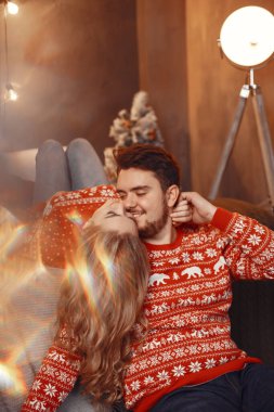 Noel süsü takmış insanlar. Kırmızı kazaklı bir adam ve kadın. Aile evde..