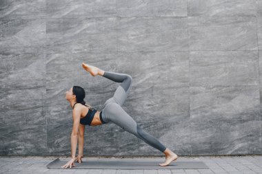 Yaz şehrinde güzel bir bayan antrenmanı. Esmer, yoga yapıyor. Spor kıyafetli bir Gitl.