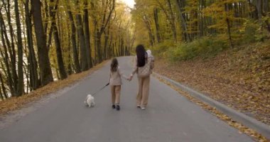Mutlu aile: anne ve çocuklar doğada sonbahar yürüyüşünün tadını çıkarıyorlar..