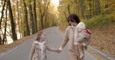 Mutlu aile: anne ve çocuklar doğada sonbahar yürüyüşünün tadını çıkarıyorlar..