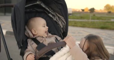 Ablam yeni doğan kız kardeşine bebek arabasında sarılıyor. Halk parkı ya da şehir merkezi. Mutlu çocuklar, kardeş kavramı..