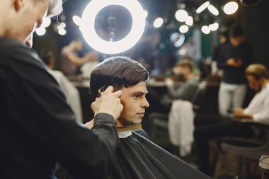 Adam saçla çalışıyor. Müşterisi olan bir kuaför..