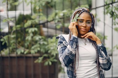 Şehir parkında gülümseyen afro saçlı genç siyahi kadın. Karışık bir kız şehirde yürüyor..