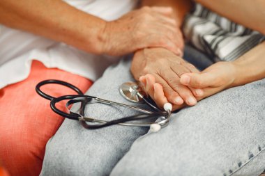 Doctor puts a heart rate monitor on a patient finger. Man holds womans hand.