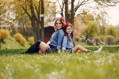 Kızı olan modaya uygun bir anne. Bir bahar parkında aile. Mavi gömlekli kadın.