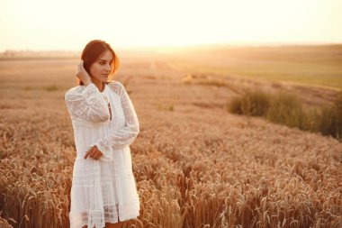 Beautiful girl in a white dress. Woman in a autumn wheat field.