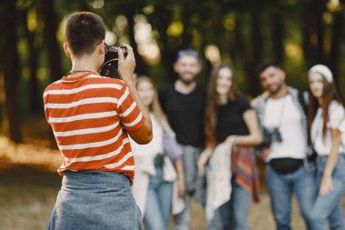 Macera, seyahat, turizm, yürüyüş ve insan konsepti. Ormanda gülümseyen bir grup arkadaş. Adam fotoğraf çekiyor..