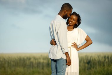 Bir tarlada kucaklaşan Afrikalı Amerikalı aşıklar.