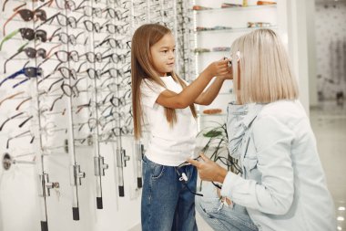 Mother with daughter. People in the store. Child in a white t-shirt.