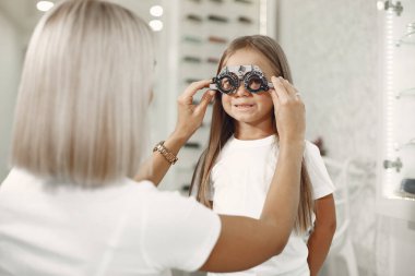 Child eye test and eye exam. Little girl having eye check-up, with phoropter. Doctor performs eye test for child.