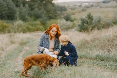 Anne ve kızı köpekle oynuyorlar. Sonbahar parkında bir aile. Evcil hayvan ve yaşam tarzı konsepti. Sonbahar zamanı.