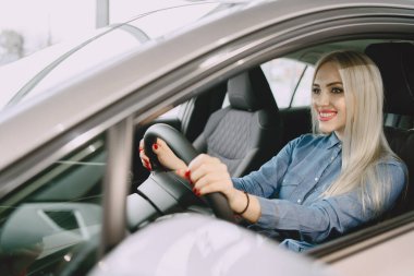 Lady in a car salon. Woman buying the car. Elegant woman in a blue dress.