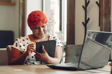 Young African American female working in an office. Lady in a white blouse.
