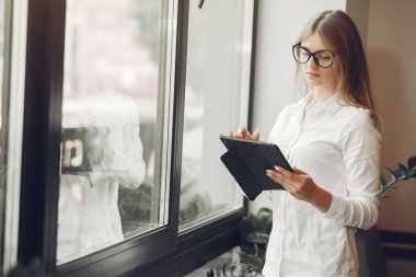 Woman working at the office. Lady with a tablet. Woman in a white blouse.