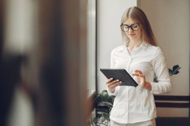 Woman working at the office. Lady with a tablet. Woman in a white blouse.
