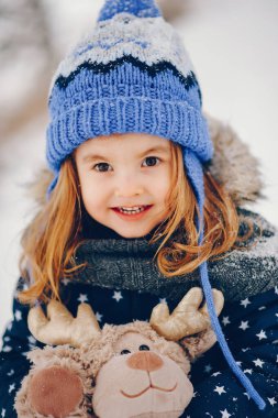 Kış ormanındaki bir çocuk. Mavi şapkalı kız. Çocuk oyuncakla oynuyor