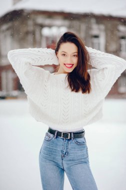 Kış şehrinde duran tatlı kız. Beyaz kazaklı kadın..