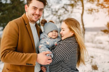 karlı bir kış gününde parkta üç mutlu genç aile