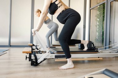 Özel bir ekipman üzerinde egzersiz yapan iki hamile kadın. Spor salonunda çalışan sağlıklı kadınlar. Gri ve siyah spor ayakkabı giyen kadınlar..