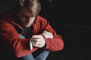 Kokain paketiyle yalnız oturan genç bağımlı adam.