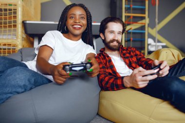Beyaz tişörtlü siyah kız. Video oyunu oynayan bir çift. İnsanlar joystick kullanır.