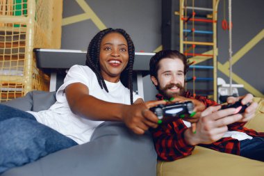 Beyaz tişörtlü siyah kız. Video oyunu oynayan bir çift. İnsanlar joystick kullanır.