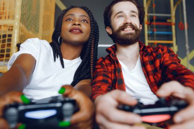 Beyaz tişörtlü siyah kız. Video oyunu oynayan bir çift. İnsanlar joystick kullanır.