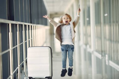 Havaalanındaki çocuk. Çantası olan küçük bir kız. Kahverengi ceketli kız..