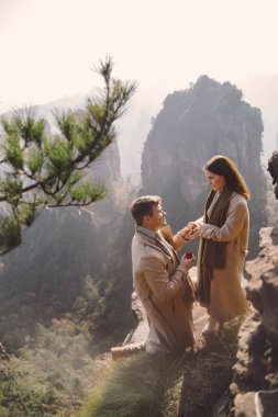 Adam Çin 'deki Zhangjiajie Ulusal Orman Parkı' nda kız arkadaşına evlenme teklif ediyor. Çin 'deki bir kayanın tepesinde evlenme teklifi. Evet dedi. Yeni nişanlı çift.