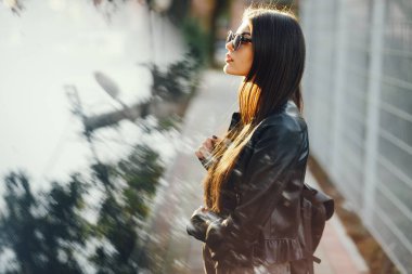 Şık bir kız sıcak bir sonbahar gününde şehirde yürüyor.