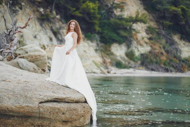 Su kenarında yürüyen muhteşem beyaz elbiseli güzel uzun saçlı gelin