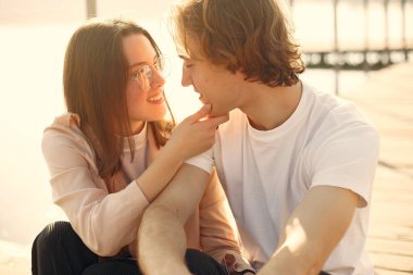 Deniz kenarında bir çift. Beyaz tişörtlü adam. Günbatımı arka planında eşleşin.