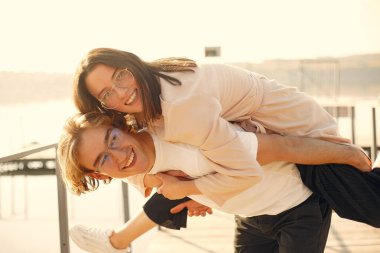 Deniz kenarında bir çift. Beyaz tişörtlü adam. Günbatımı arka planında eşleşin.