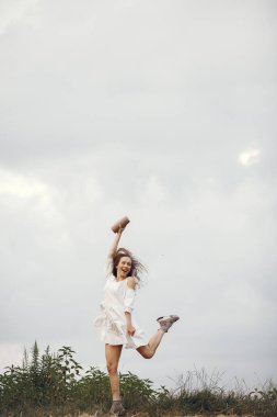 Yaz tarlasında bir kadın. Beyaz elbiseli esmer. Müzik hoparlörü olan kız.