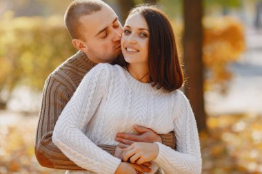 Parkta bir çift. Beyaz kazaklı kadın. Kahverengi kazaklı adam..