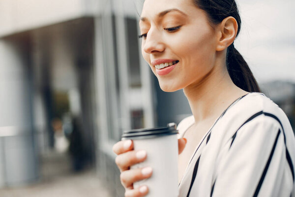 Beautiful girl in a city. Stylish girl near gray building