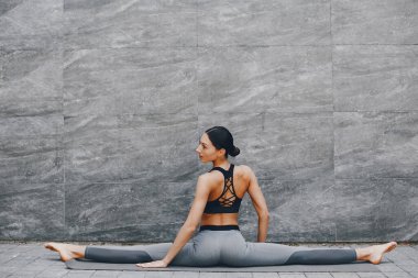 Yaz şehrinde güzel bir bayan antrenmanı. Esmer, yoga yapıyor. Spor kıyafetli bir Gitl.