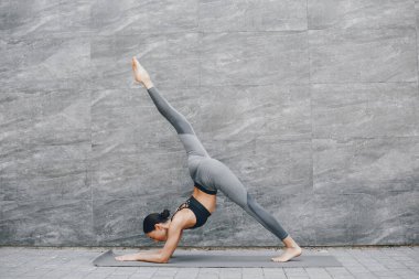 Yaz şehrinde güzel bir bayan antrenmanı. Esmer, yoga yapıyor. Spor kıyafetli bir Gitl.