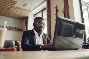 African man. Guy in a black suit. Male with a laptop. Businessman at the office.