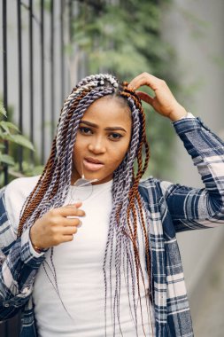 Şehir parkında gülümseyen afro saçlı genç siyahi kadın. Karışık bir kız şehirde yürüyor..