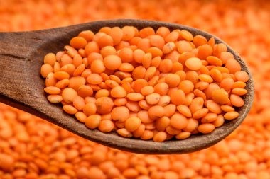 Çerçeveyi dolduran kırmızı mercimek ve tahta bir kaşık tarafından kaldırılmak.