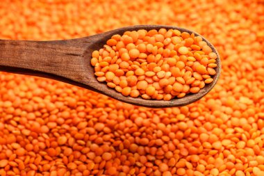 Çerçeveyi dolduran kırmızı mercimek ve tahta bir kaşık tarafından kaldırılmak.