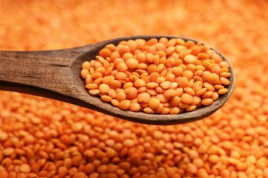 Çerçeveyi dolduran kırmızı mercimek ve tahta bir kaşık tarafından kaldırılmak.