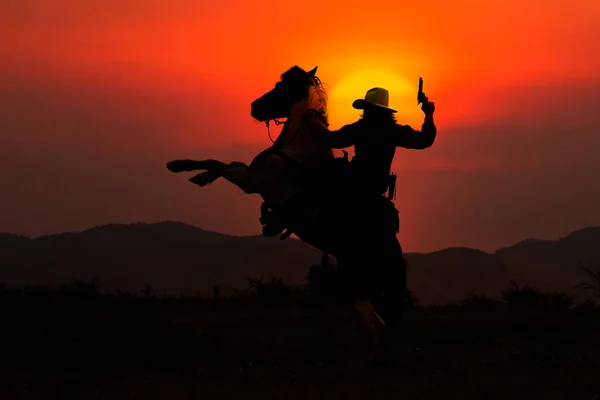 Siluet Koboi Atas Kuda Dan Matahari Terbenam Sebagai Latar Belakang Stok Gambar
