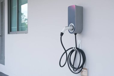 Ev veya hibrit arabayı şarj etmek için elektrik kablosu takılı modern elektrikli araç (Ev) Beyaz Saray duvarında izole edilmiştir..