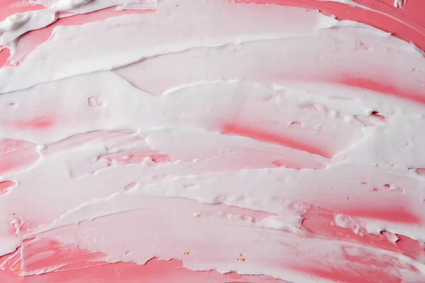 White facial cream smears on pink background. Surface covered by cream
