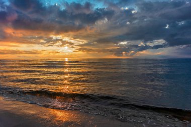 Deniz kenarındaki kumsalda büyüleyici gün batımları.