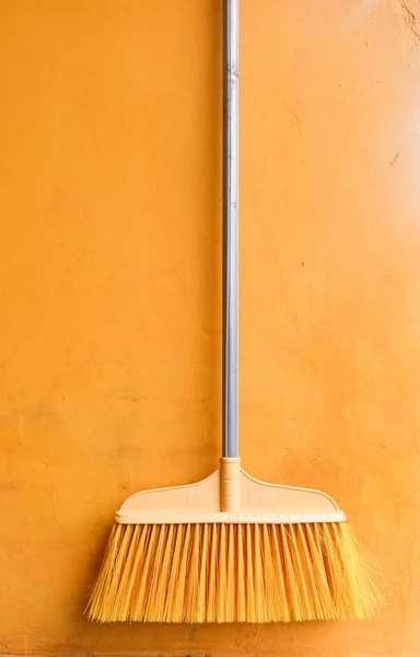 Isolated object: Household Appliances Plastic wooden handle broom, on yellow background