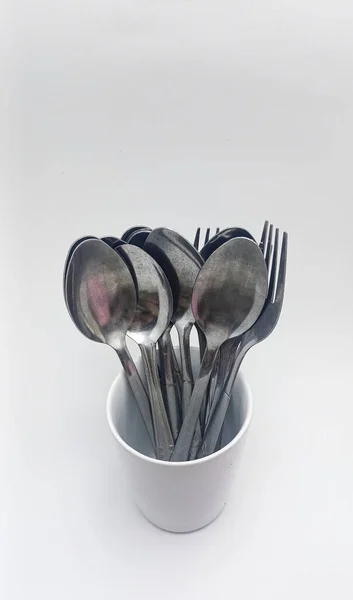 Isolated objects: spoon and fork in a white glass, on a white background