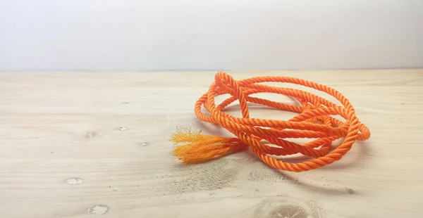 Isolated Object: orange rope medium size, on a wooden background